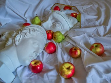 Antik Yunan beyaz heykeli, Diana 'nın alçı heykeli, David' in gözü, altın çerçeveli bir aynaya, yeşil armut ve kırmızı elmalı katlanmış beyaz kumaştan oluşan bir arka plana yansıyor.