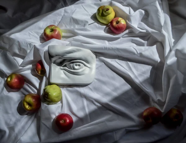 Antik Yunan heykeli beyaz alçı mermer mermer David 'in arka plandaki beyaz kumaşlı, armutlu ve hafif kırmızı elmalı kumaşına karşı.