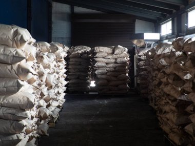 Kömür fabrikasında, kömürle dolu tam kahverengi kese kağıdı torbaları, arka plan desteleri.