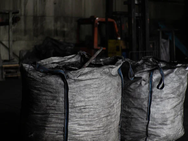 Cloth fleecy white agricultural bags with coals, inside a shovel, coal factory