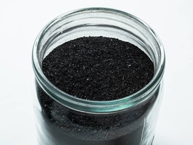 Kozmetik yüz maskesi için aktive edilmiş karbon tozu bir cam kavanozda, beyaz sırt üzerinde yan görüş