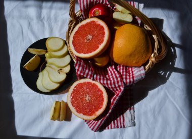 Parlak kırmızı turuncu greyfurt ve sepetin tamamını kes ve beyaz arka plan kumaşında armut kes. Güneş ışığı altında, gölgeli, elmalı ve elmalı.