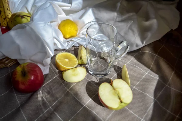 成熟的果实 红色的苹果 在白色的 有褶皱的果皮上切柠檬 在有玻璃和苹果片的格子毛毯上 阳光照射下 — 图库照片