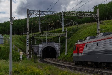 Tren yolu, tren yolu yeşil dağlardaki tünelle ağaçlar, teller, gökyüzündeki bulutlar
