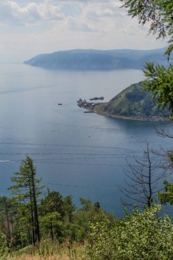 Mavi göl kıyısındaki kayalıkların tepesindeki yeşil dağlar Angara Nehri 'nin ağzındaki Chersky Taşı, kozalaklı ağaçlar