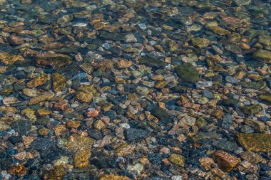parlak renkli küçük çakıl taşları berrak suda parlıyor güneşte parlıyor, sabah gölü baykal