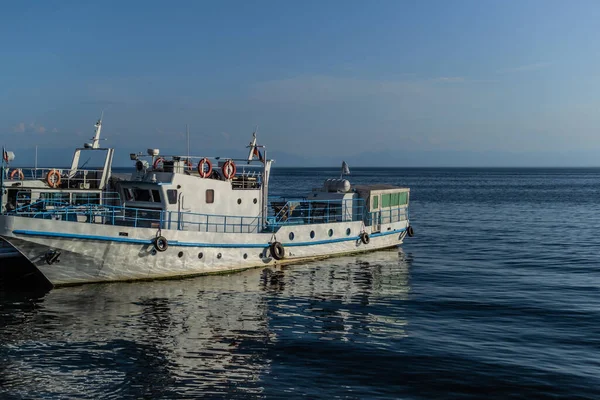 Baykal Gölü 'nün körfezinde mavi çizgili beyaz bir tekne. Güneş ışığı altında, ufukta yansımaları var.