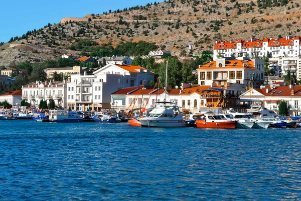 Renkli binaların yakınındaki marinalardaki parlak beyaz tekneler tatil köyü kayığında dağların arasında.