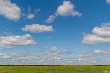 Beyaz kabarık parlak bulutlar mavi gökyüzünde yeşil alan, açık alan