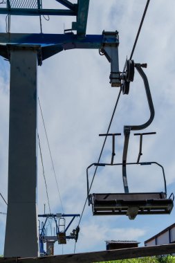 Koltuklu eski teleferik sütun inşaatı, güneşli yaz gökyüzü beyaz bulutlu