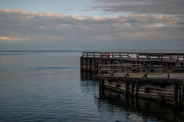 老的木制大墩耸立在湖岸上 黄昏时分在海滨的水面上反射出涟漪 — 图库照片