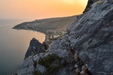 Kayalık uçurum, sahil, Karadeniz körfezi, tepelerin ve yüksek dağların arasındaki kasaba. Kırım, yaz kızıl gün batımı manzarası