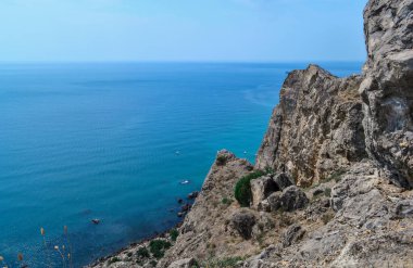 Karadeniz kıyılarının arka planında yeşil ağaçlarla büyük dik kayalık uçurumu, yaz manzarası