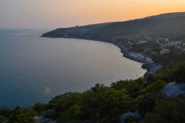 Günbatımı sahili, Karadeniz körfezi, tepeler arasında kasaba, Kırım, yaz manzarası.