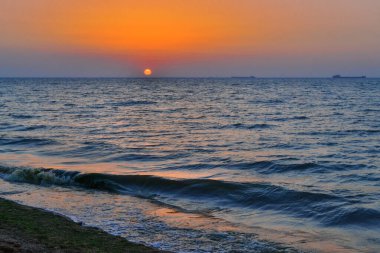 Parlak güneş çemberi sarı pembe turuncu şafak dalgalı denizde, günbatımında