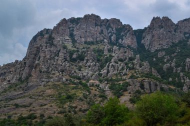 Demerdzhi 'deki Hayaletler Vadisi' nde (Demerji) kayaların aşınmasıyla oluşmuş güzel taş heykellerin manzarası. Yüksek dağlar. Ön planda yeşil çalılar