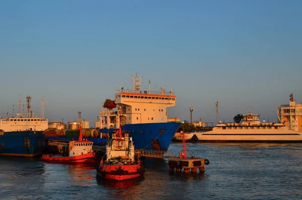 大きな白い青い船 赤いボート 港にドッキング船 暖かいオレンジ色の夕日の光と工業港の一般的なビュー — ストック写真