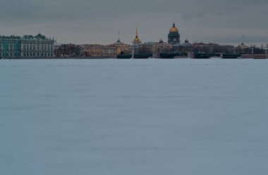Saint Petersburg 'da kış seti, temiz renkli binalar ve donmuş karlı Neva nehrinin kıyısındaki St. Isaac Katedrali.