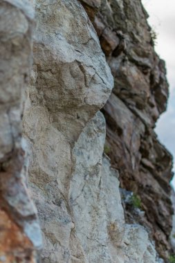 sert taş hafif kaya, kahverengi bej kayalık. Farklı katmanlarda levhalar. Bulutlu. Baykal Dağları