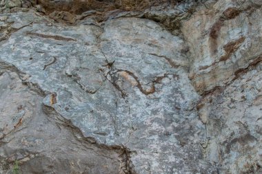 Yılan desenli pürüzsüz, taştan hafif kayalar, çatlaklı kahverengi bej uçurumlar. Farklı katmanlarda levhalar. Bulutlu. Baykal Dağları