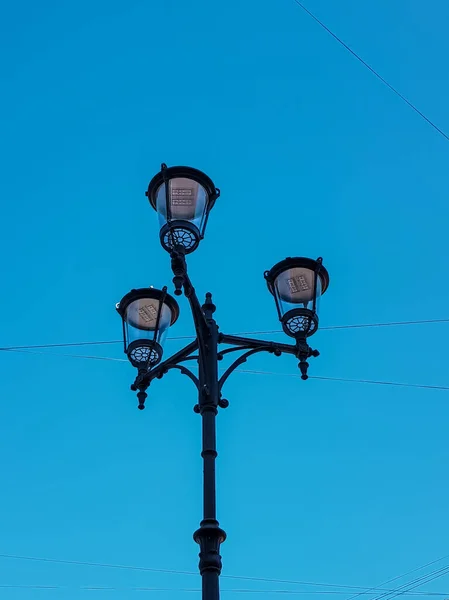 古老的黑色装饰灯笼 柱子上有透明的玻璃 一根杆子上有三盏路灯 阳光明媚的蓝天梯度 圣彼得堡市 — 图库照片