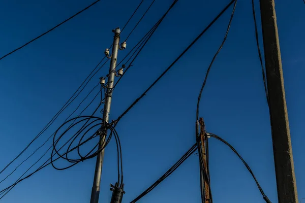 Power lines, electric poles with black wires on bright blue sky gradient backdrop