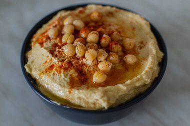 Ev yapımı kremalı humus, vejetaryen mutfağında koyu tabakta nohut ve kırmızı baharat. Üst görünüm