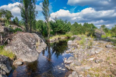 Bulutlu gökyüzü ile dağlarda akarsu