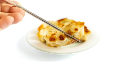 Hamur köfteleri kızartma yağıyla kaplı bir tavada kızartılmış ve bir tabakta servis edilmişti. Onları yemek için çubuklarla hamur köftesi topladım..