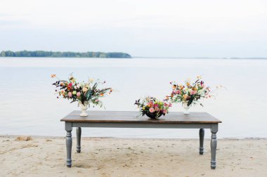 Doğada ahşap masa. Şık bir düğün çiçeği dekoru. Düğün çiçekleri masada.