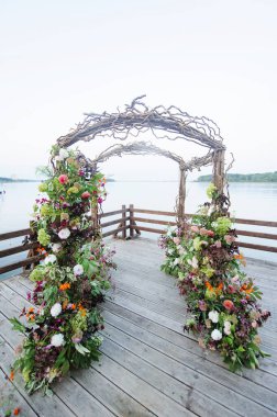 Kuru ağaçlardan ve göletin yakınındaki çiçeklerden yapılmış taşralı düğün kemeri.