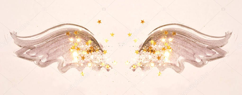 Golden glitter and glittering stars on abstract black watercolor wings in vintage nostalgic colors.