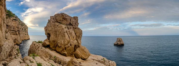 Gün batımında bir uçurumdan panoramik manzara. Denizden çıkan küçük bir adacık ile