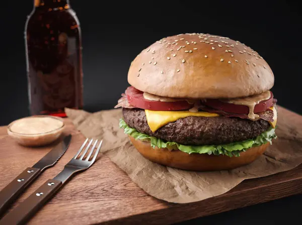 Closeup of Big Single Burger with Beer bottle and spoons
