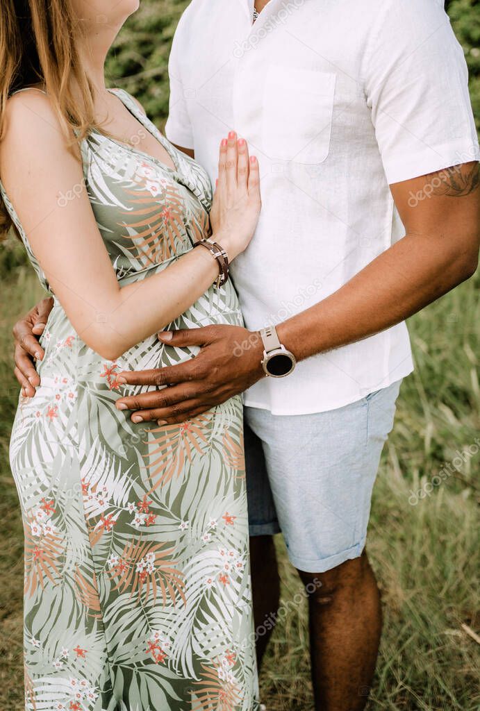 a pregnant interracial couple hugging in the woods