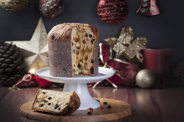 Ahşap bir masada servis edilen panettone arkaplanı bulanık ve noel süslemesi