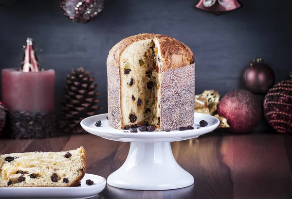 Panettone beyaz bir tabakta servis edilir ahşap bir masada arkaplan bulanıklaşır yılbaşı süsüsüyle