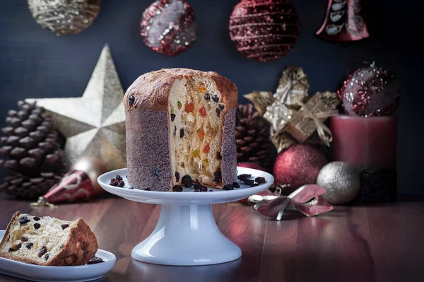 Panettone beyaz bir tabakta servis edilir ahşap bir masada arkaplan bulanıklaşır yılbaşı süsüsüyle