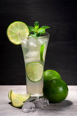 Dilimlenmiş mojito ve tüm limonlar, mermer bir masada buzlar koyu arkaplanlı.