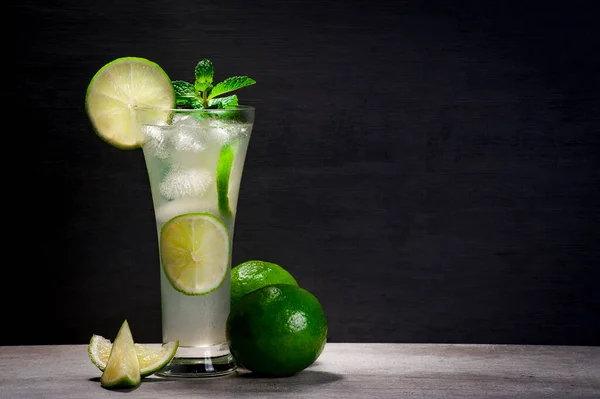 Mermer bir zemin üzerinde mojito kokteyli koyu arkaplan ve dilimler ve tüm limonlar, kopyalama alanı