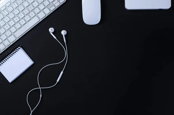 Ofis çalışma alanının üst görüntüsü, klavyesi, faresi, defteri ve harici hard diski olan siyah masa. Kopyalama alanı ile, düz uzanır.