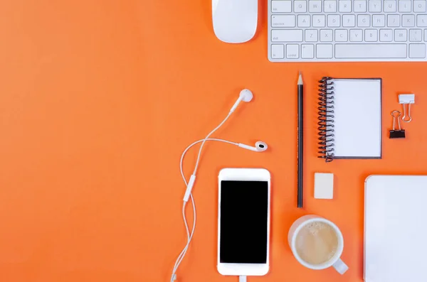 Ofis çalışma alanının en üst görüntüsü, klavyeli turuncu masa, kalem, kulaklık, cep telefonu, fare, defter ve kahve. Kopyalama alanı ile, düz uzanır.