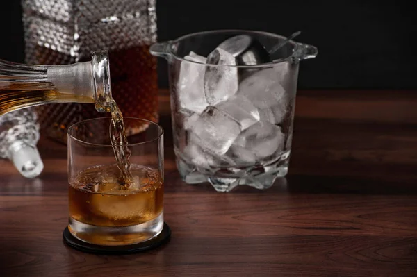 Bir bardak viski ve ahşap masada bir şişe.