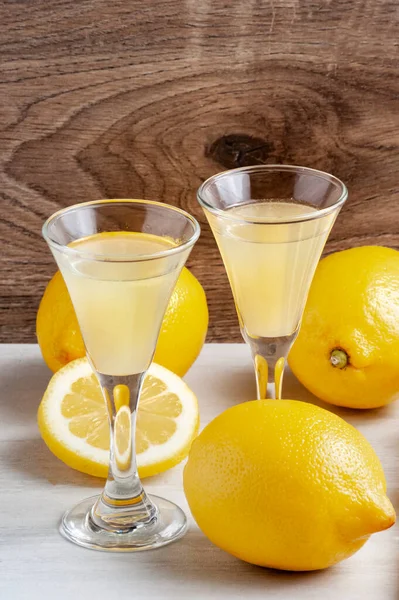 İki küçük bardakta taze sıkılmış limon suyu, bütün limon ve ahşap arka plan..