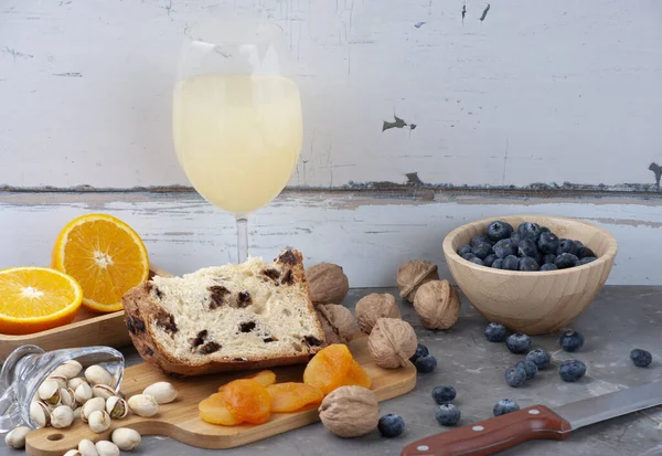 Noel panettone dilimi, kuru üzüm ve mermer masada kurutulmuş meyve. Portakal dilimi, şam fıstığı, yabanmersini, bıçak, fındık ve kurutulmuş kayısı. Seçici odak, boşluğu kopyala.