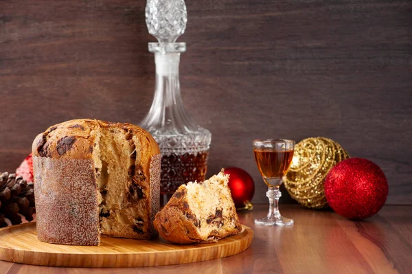 Ahşap bir tepside dilimlenmiş Panettone, bir bardak likör ve noel süsü. Seçici odak, boşluğu kopyala.