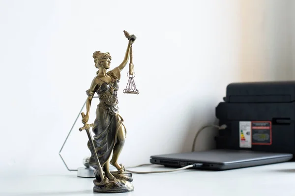 Justice symbol in a law firm on a desk beside a laptop