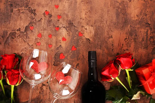 Composition for Valentine\'s Day.  Roses, gift, glasses and wine, red hearts. Top view.