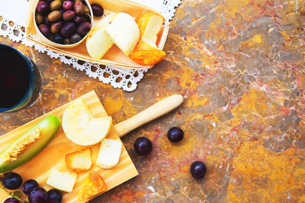 Still life of cheese, fruit, wine on a natural marble surface