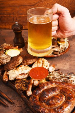 Et Mangal masaya ayarla. Sosis, domuz eti, mantar, sığır eti, sosları, turşu. Bira aperatifler.